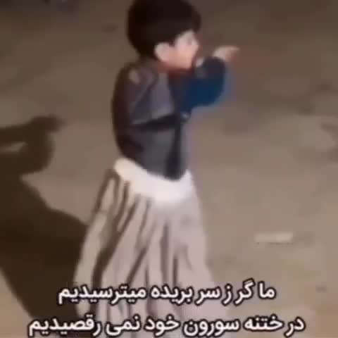 کودکی با لباس بلند و کت آبی در میدانی شبانه می‌رقصد؛ متن شعری طنز درباره رقصیدن در جشن ختنه‌سوران است.